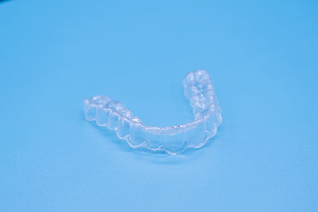 Clear plastic aligner on a blue background.